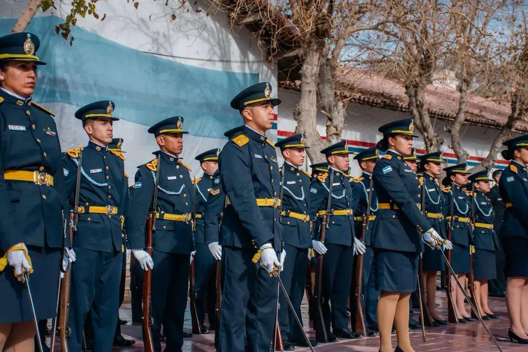 Formación de cadetes en uniforme de gala, con la bandera argentina de fondo